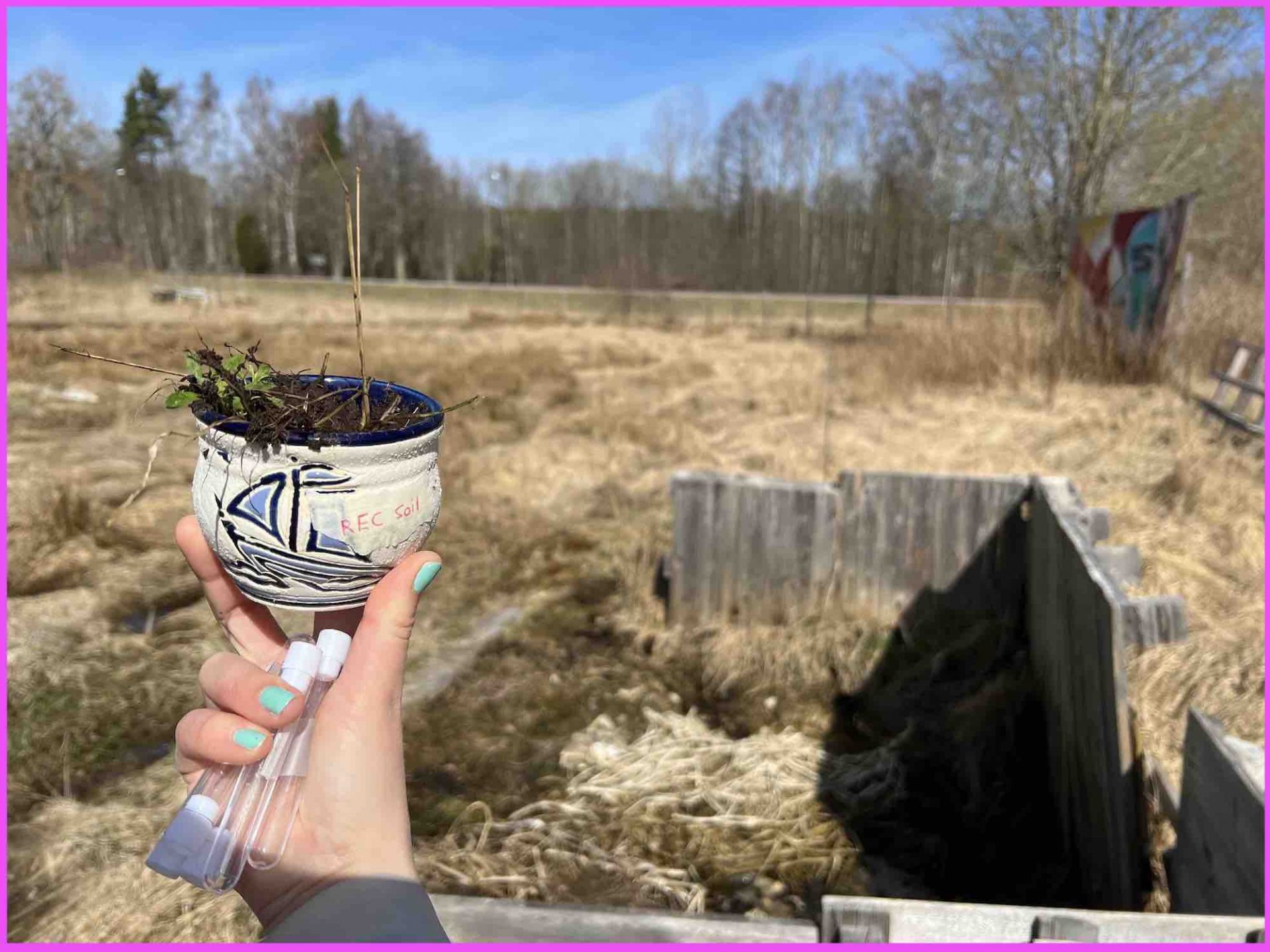 Photo of soil sample in a small pot with farm in background