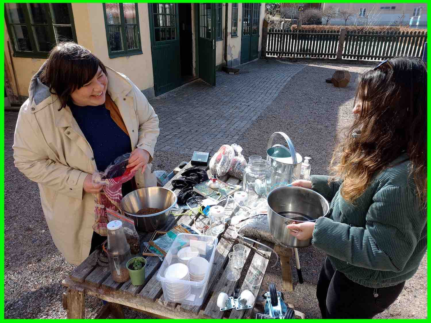 Helen and Smaranda standing outdoors in front of a table full of bubble bioremediation tea components