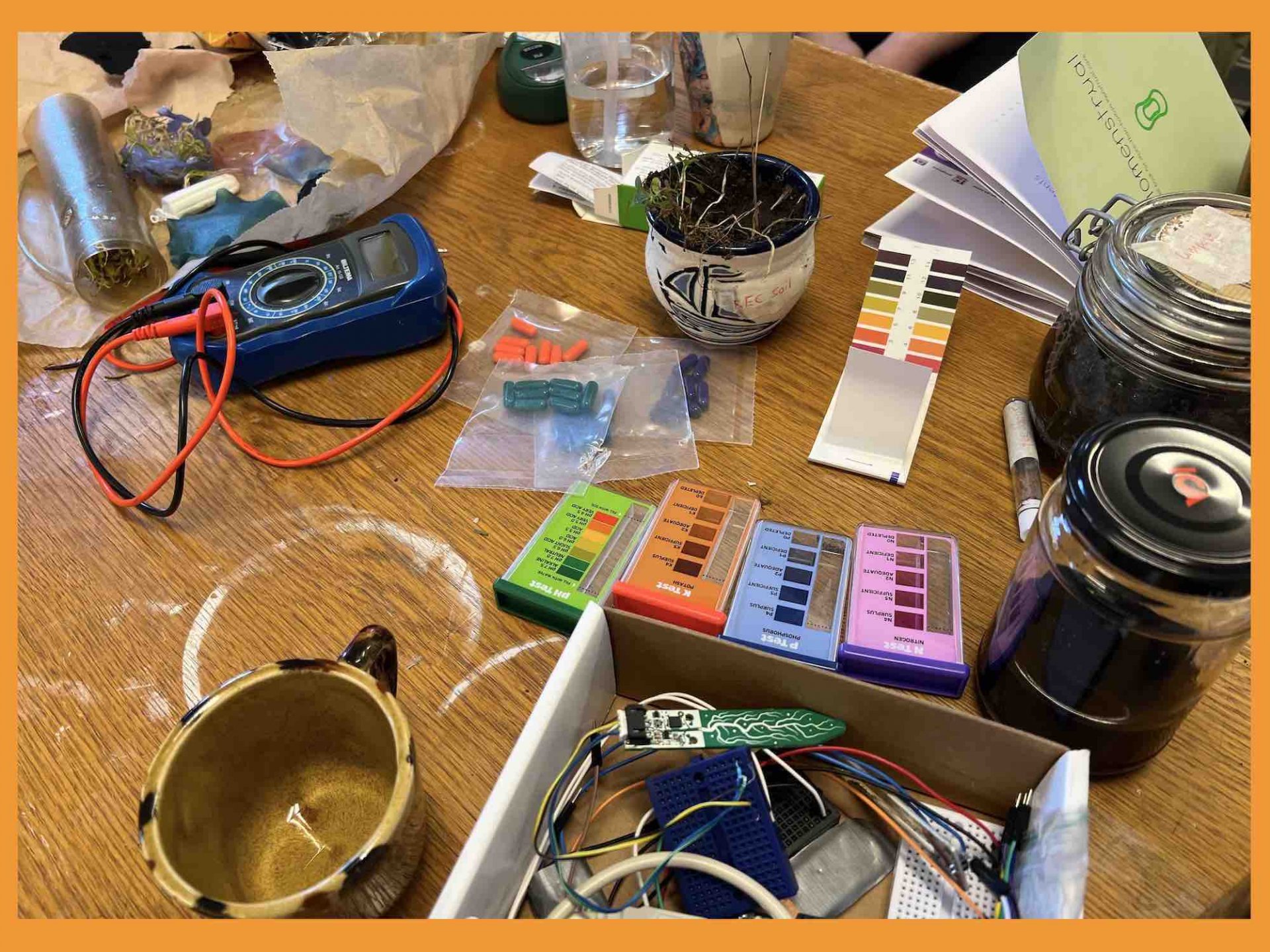 Busy studio table with NPK testing kits, soil samples and electronics