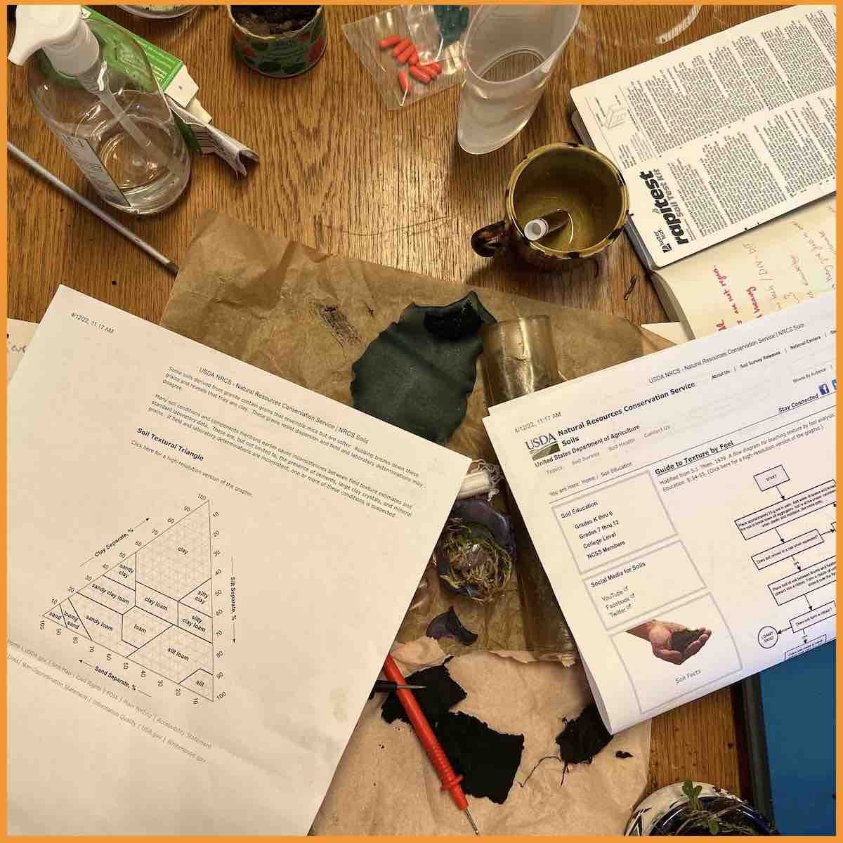 Photo of studio table with soil categorisation flow diagrams and other items used in the workshop